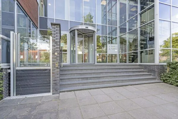 Ingang van een modern kantoorgebouw aan de Fascinatio Boulevard met een glazen gevel en draaideur.